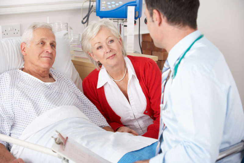 Doctor talking to senior couple on UK Hospital ward