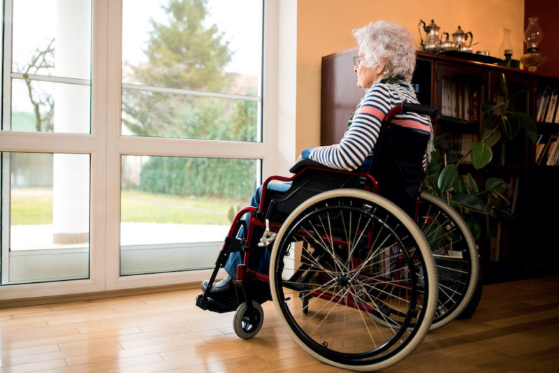 Loneliness senior woman sitting in wheelchair at nursing home, forgotten by the family